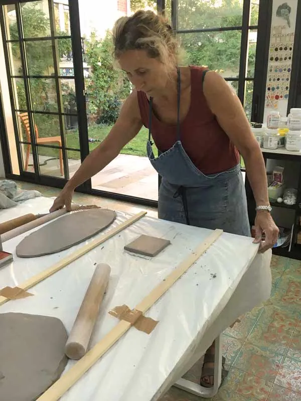 Façonnage manuel d'une dalle de terre crue dans l'atelier